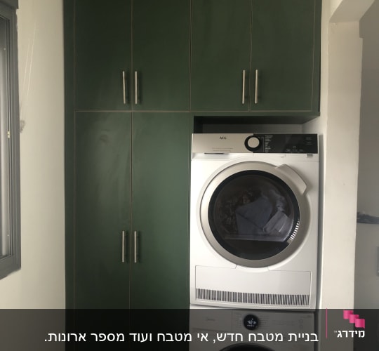 ארון ירוק עם ידיות מתכת ליד מכונת כביסה